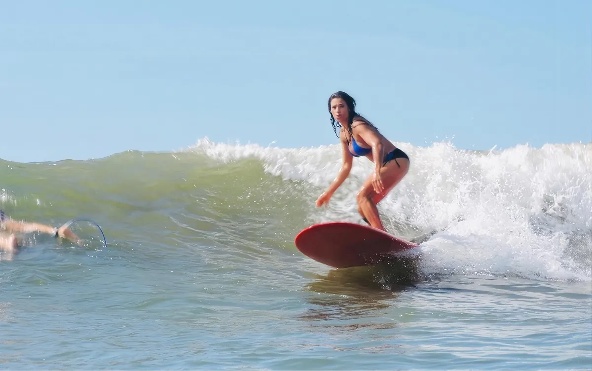 Neide Ferreira surfando numa prancha vermelha